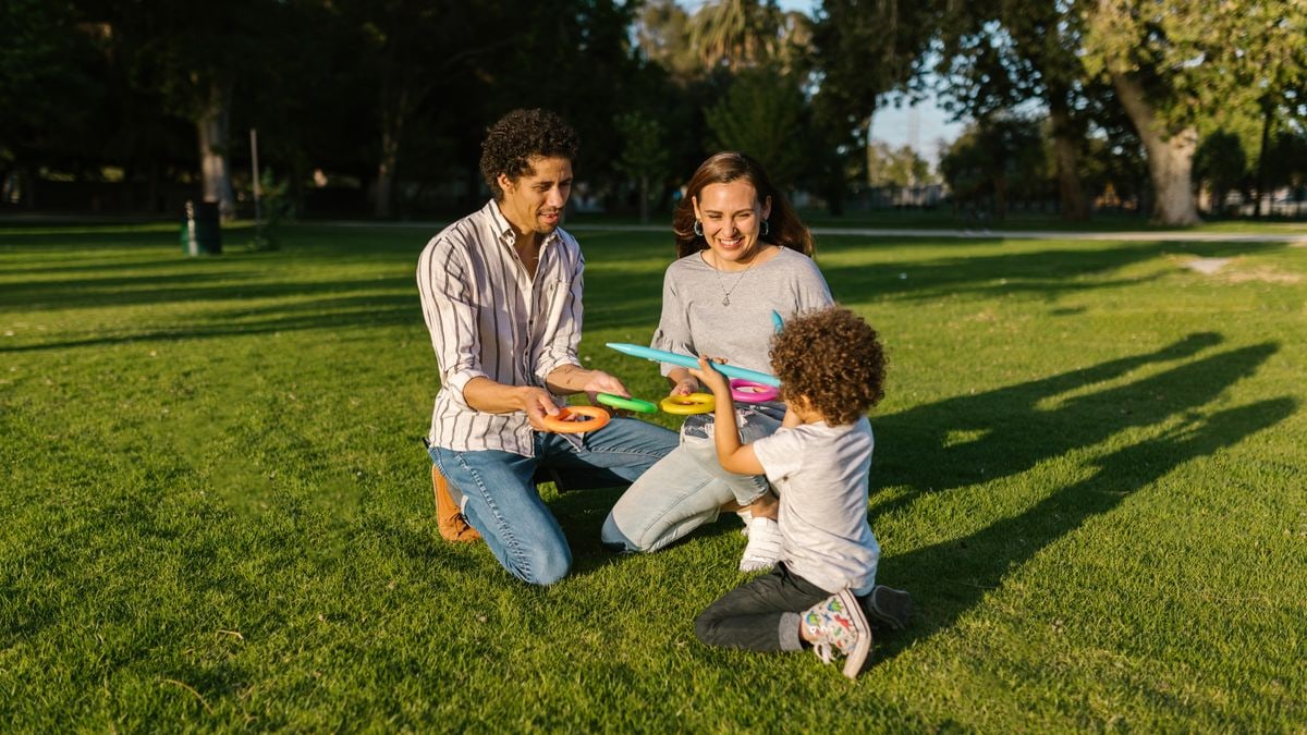 Family playing ring toss together enjoying sunny day in park.